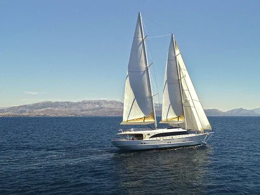 A majestic sailing yacht with white sails glides A majestic sailing yacht with white sails glides